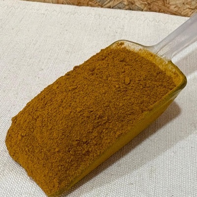 Pá transparente com pó castanho alaranjado sobre tecido branco e fundo de madeira