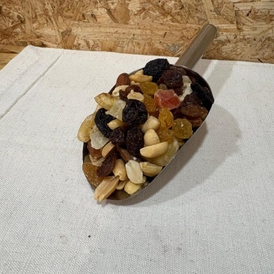 Pá com mistura de frutos secos variados sobre superfície branca e fundo de madeira