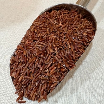 Colher de metal cheia de arroz vermelho cru