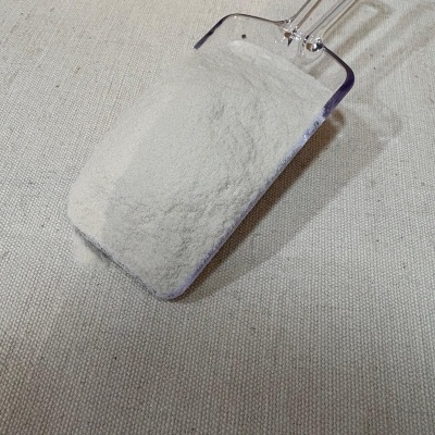 Pá plástica transparente com pó branco sobre tecido bege texturizado