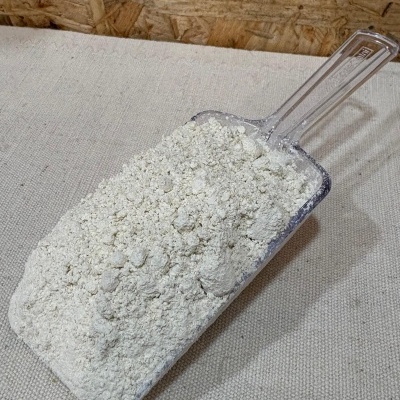 Pá plástica com pó branco sobre tecido bege e fundo de madeira