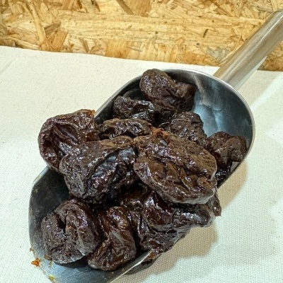 Pá metálica com frutos secos pretos sobre tecido branco