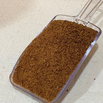 Pá transparente com pó castanho fino sobre superfície beige