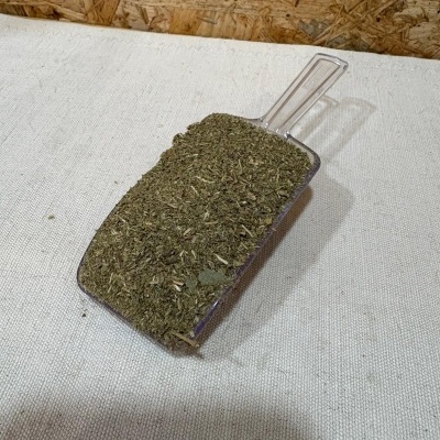 Colher de plástico transparente com ervas secas verdes sobre tecido branco