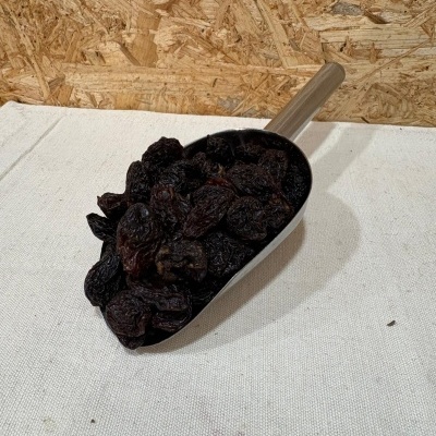 Pá metálica com passas secas pretas sobre tecido branco