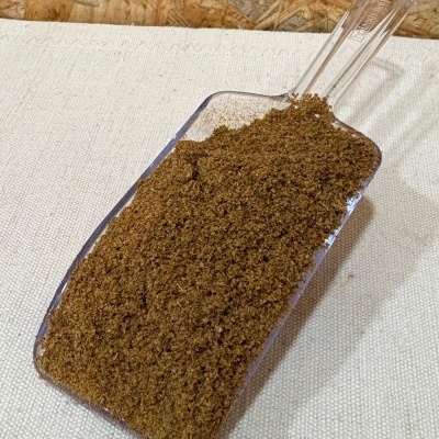 Pá de plástico transparente com pó marrom sobre tecido branco