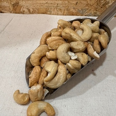 Concha metálica cheia de cajus descascados sobre tecido bege clara e fundo de madeira OSB