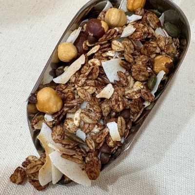 Pá de metal com granola variada sobre tecido bege.