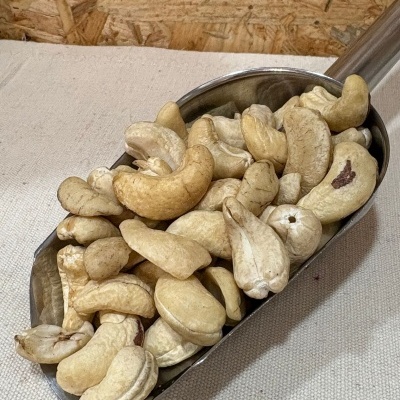 Castanhas de caju inteiras em scoop metálico sobre tecido bege