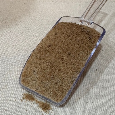 Pá transparente com pó marrom claro em superfície de tecido bege