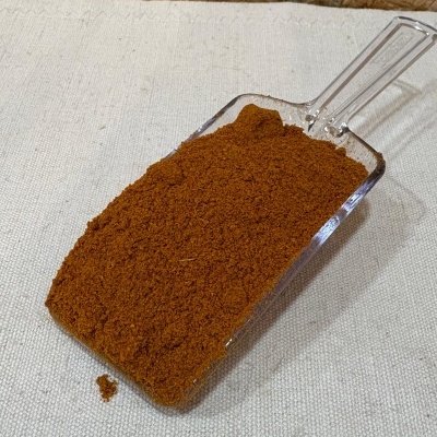 Pá de plástico transparente com pó castanho avermelhado sobre tecido bege