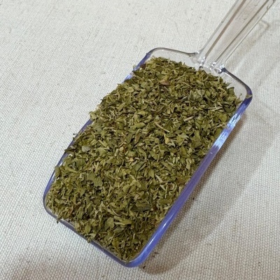 Pá plástica transparente com folhas secas verdes sobre tecido bege