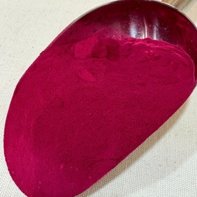 Pá metálica com pó vermelho-púrpura sobre tecido bege