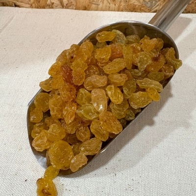 Concha metálica com uvas-passas amarelas sobre tecido branco