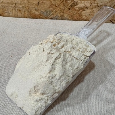 Pá de plástico transparente cheia de farinha branca sobre pano bege