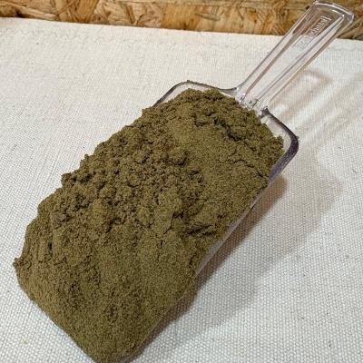 Pá transparente cheia de pó verde sobre tecido bege