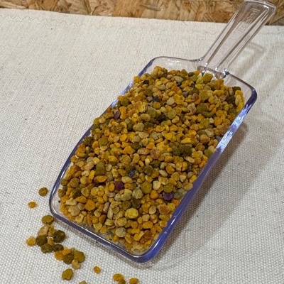 Colher de plástico com bolinhas coloridas amarelas, verdes e laranja sobre tecido bege