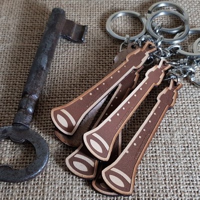 Chave antiga de metal com ferrugem e quatro porta-chaves de madeira em forma de bolota sobre tecido castanho texturado.