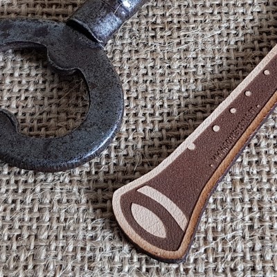 Faca com cabo de couro marrom e anel metálico sobre tecido de juta
