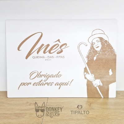 Placa comemorativa branca com texto castanho e imagem estilizada de mulher com chapéu e bengala