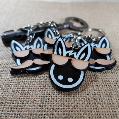 Chaveiros de plástico com cabeça de animal estilizada e óculos de sol sobre tecido castanho