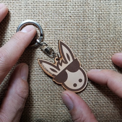 Chaveiro de cabeça de burro com óculos feito em madeira sobre superfície bege