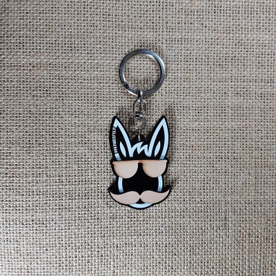 Chaveiro de cabeça de animal com óculos e bigode sobre tecido rústico