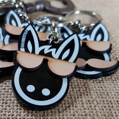 Chaveiros de ovelha em acrílico preto, branco e bege sobre tecido de juta