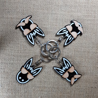 Porta-chaves estilizados em forma de cabeça com óculos escuros sobre tecido bege