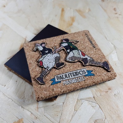 Objeto de cortiça com figuras tradicionais e texto 'PAULITEIROS BISINDA S.S.' num fundo de madeira