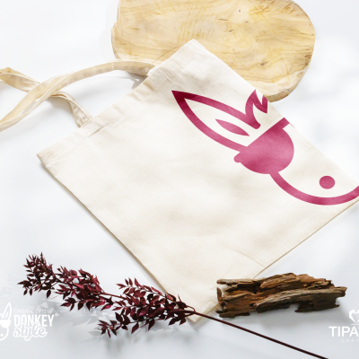 Saco de tecido creme com estampa vermelha e elementos naturais ao redor