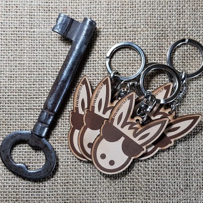 Chave antiga de metal e três porta-chaves com rosto de burro sobre tecido rústico