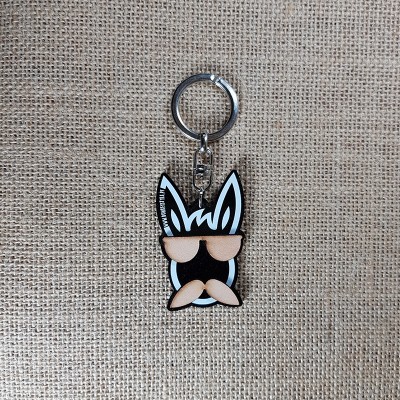 Chaveiro em forma de cabeça de coelho com óculos e bigode sobre tecido tipo juta