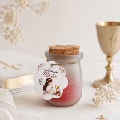 Frasco de vidro fosco com tampa de cortiça e etiqueta de primeira comunhão numa mesa com cálice dourado e decoração floral seca