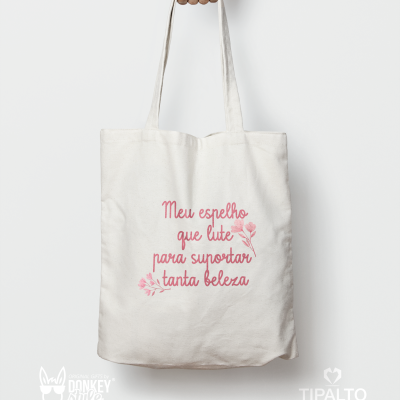 Saco de tecido branco com frase em português em rosa e desenhos de flores.