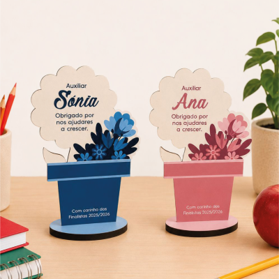 Duas esculturas decorativas em forma de vaso com flores de papel, azul e rosa, com mensagens de agradecimento, em mesa com material escolar e planta