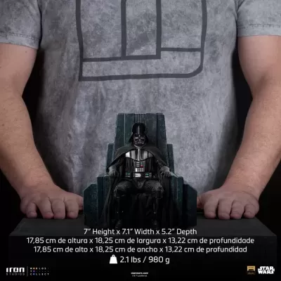 Estatueta Darth Vader sentado em cadeira escura, mãos de pessoa e t-shirt cinzenta ao fundo