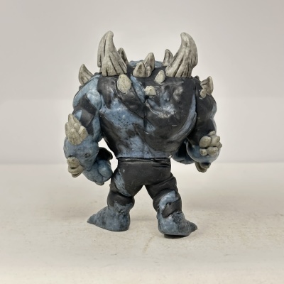 Boneco de ação com espinhos e garras cinzentos, corpo azul e preto visto de costas