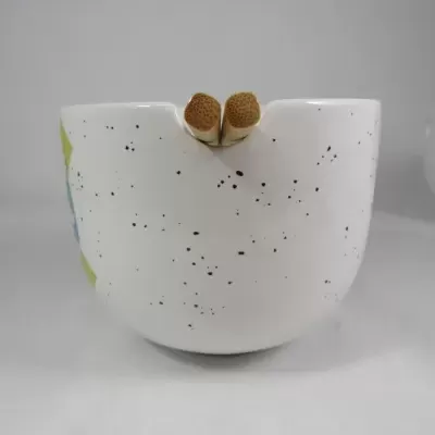 Caneca branca com pontos pretos e paus de canela na borda.