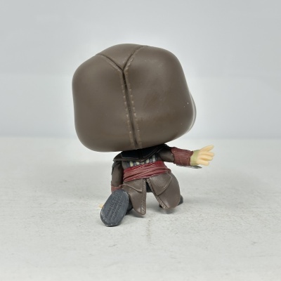 Figura colecionável vista de costas com cabeça grande castanha e roupas detalhadas.
