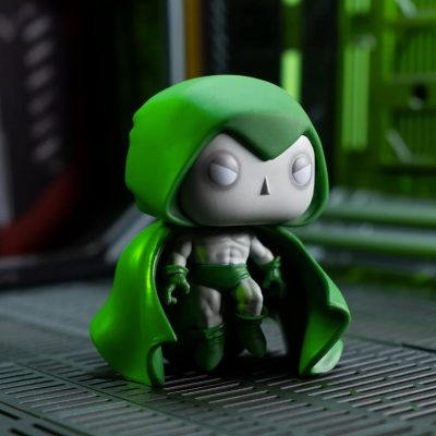 Figura de vinil com capa e capuz verde num cenário industrial metálico.