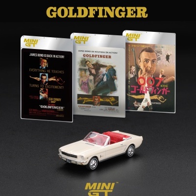 Miniatura de carro branco descapotável com interior vermelho e cartazes do filme Goldfinger em fundo preto.