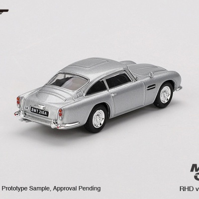 Miniatura de carro clássico prateado com matrícula BMT 216A e texto 007, MINI GT numa superfície branca.