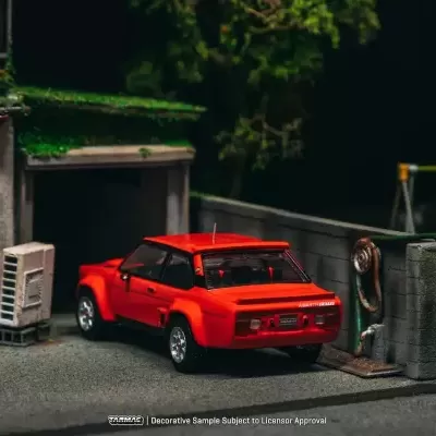 Miniatura de carro vermelho Abarth junto a garagem com parede cinzenta e caixa de correio vermelha