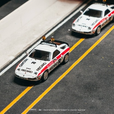 Miniaturas de carros de polícia brancos com detalhes vermelhos e luzes amarelas numa estrada em miniatura.