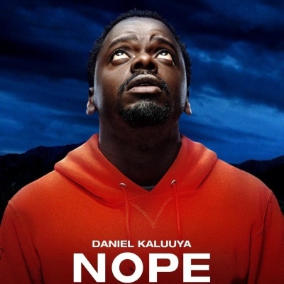 Homem com hoodie laranja olhando para cima com céu noturno ao fundo e texto 'DANIEL KALUUYA NOPE'
