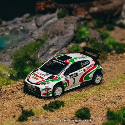 Miniatura de carro Toyota de corrida com decoração Castrol verde, vermelha e branca em terreno com pedras e vegetação