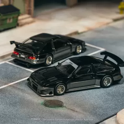 Miniaturas de carros desportivos pretos estacionados em cenário urbano em miniatura.