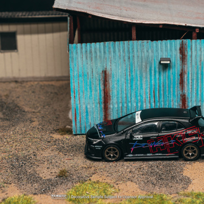 Miniatura de carro preto com texto vermelho preto junto a parede de chapa azul