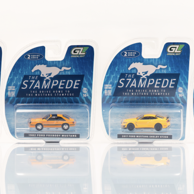 Seis miniaturas de carros Ford Mustang em embalagens com fundo azul e texto THE STAMPEDE